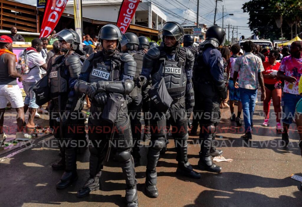 Cops in riot gear keep a close eye on proceedings during J'Ouvert celebrations in Crown Point last Saturday. - David Reid