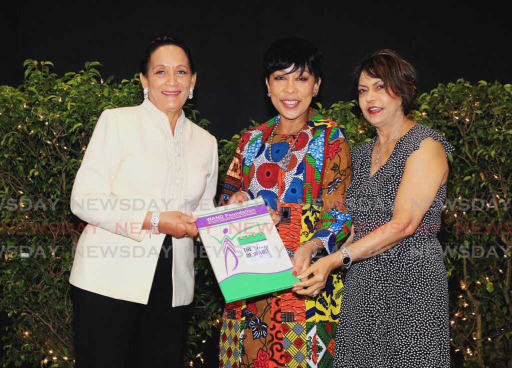 WAND president Mona Khan, right, and board member Jan Bocas Ryan, left, present Sharon Rowley, wife of the Prime Minister, with a copy of  The Story of WAND during a fundraising luncheon at Hyatt Regency, Port of Spain on Friday.  Photo by Roger Jacob