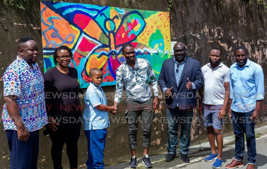 Speyside Secondary student Quishang Jacob, 12, is congratulated by Chief Secretary Farley Augustine as his painting, Pollinator, hangs on a wall on Speyside main road on Thursday. Looking on are his mother Priscilla Jacob, second from left, THA official Nigel Taitt, third from left, and others.  - David Reid