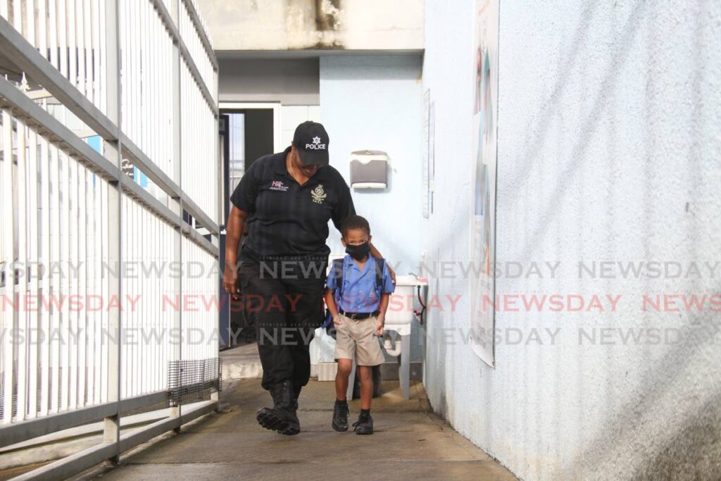 Cpl Marcano Phillip walks a student if the Rose Hill Primary School on the compound on La Coule Street,  Port of Spain as school re-opened after being closed for one because of gun shots in the area.  Photo by Ayanna Kinsale