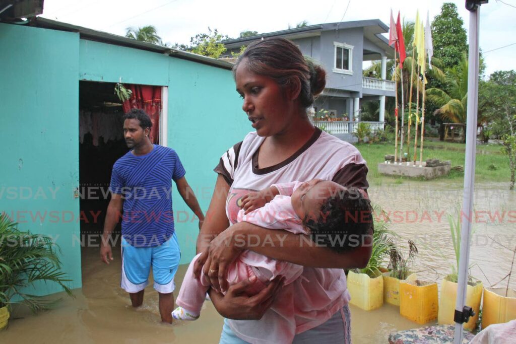 Sara Baboolal holds her two-month-old baby as she speaks with Newsday about how the constant flooding is affecting her family. In the background is her husband Kevin Roopchan. Photo by Marvin Hamilton