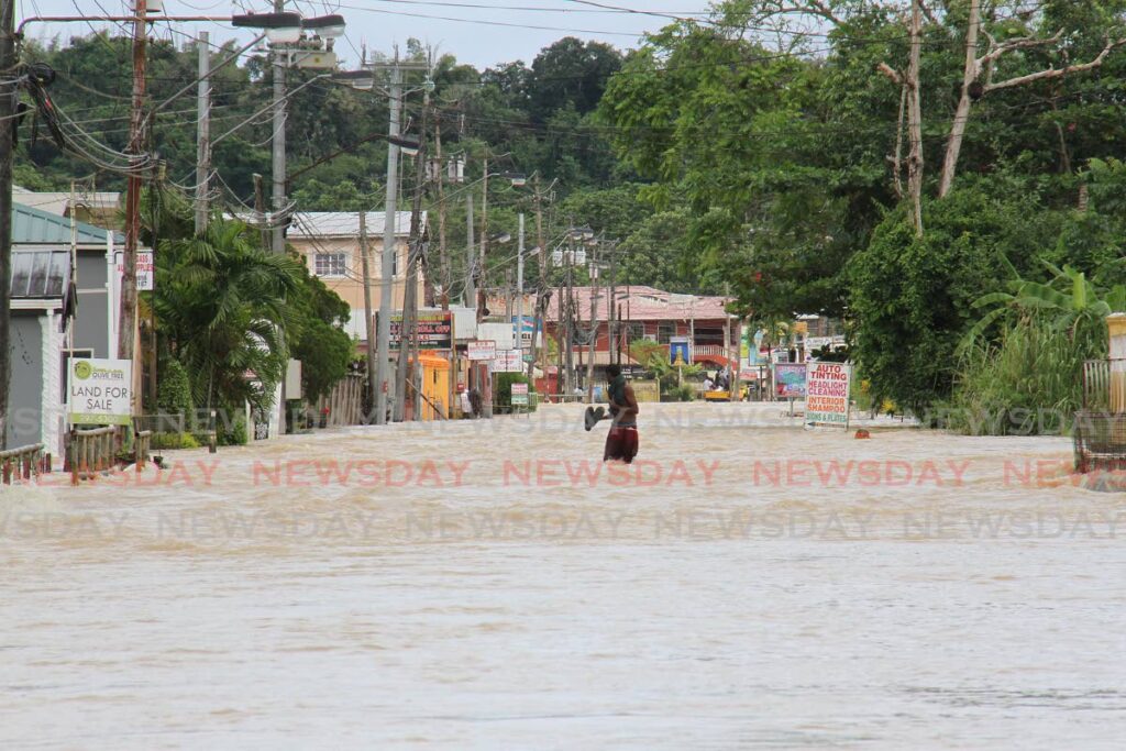 Slippers in hand, this man walks through the flood at Penal Rock Road on November 9. File photo/Marvin Hamilton