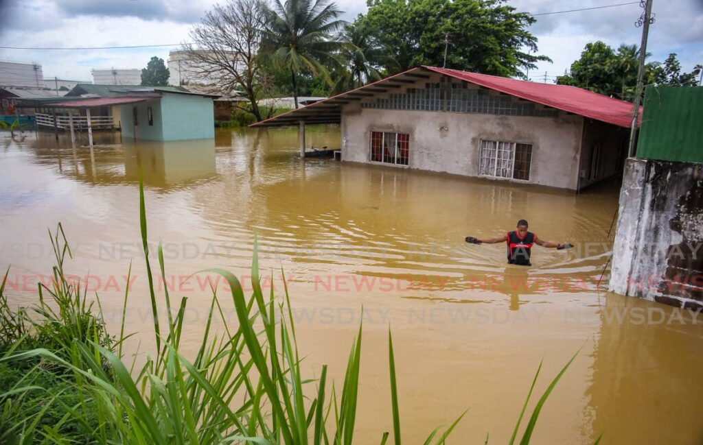In this November 9 photo, Ordell Jackson walks through floodwaters in Carli Bay, Couva after torrential rain. - FILE PHOTO/LINCOLN HOLDER