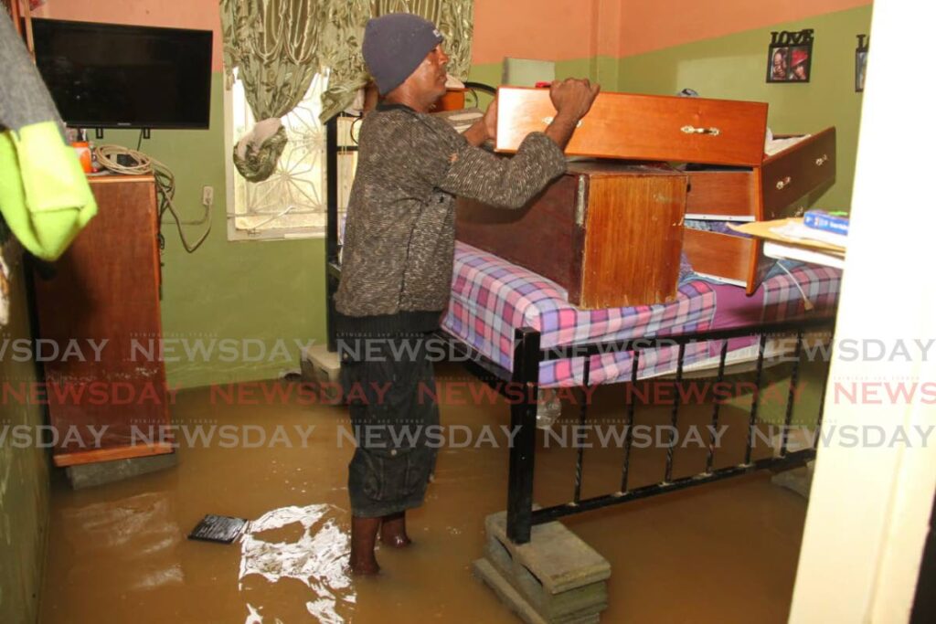 Tyrone Reece shows the household items he assisted his neighbour in placing on higher ground as her house Toco Main Road, Sangre Grande, remained flooded on Thursday. - Ayanna Kinsale