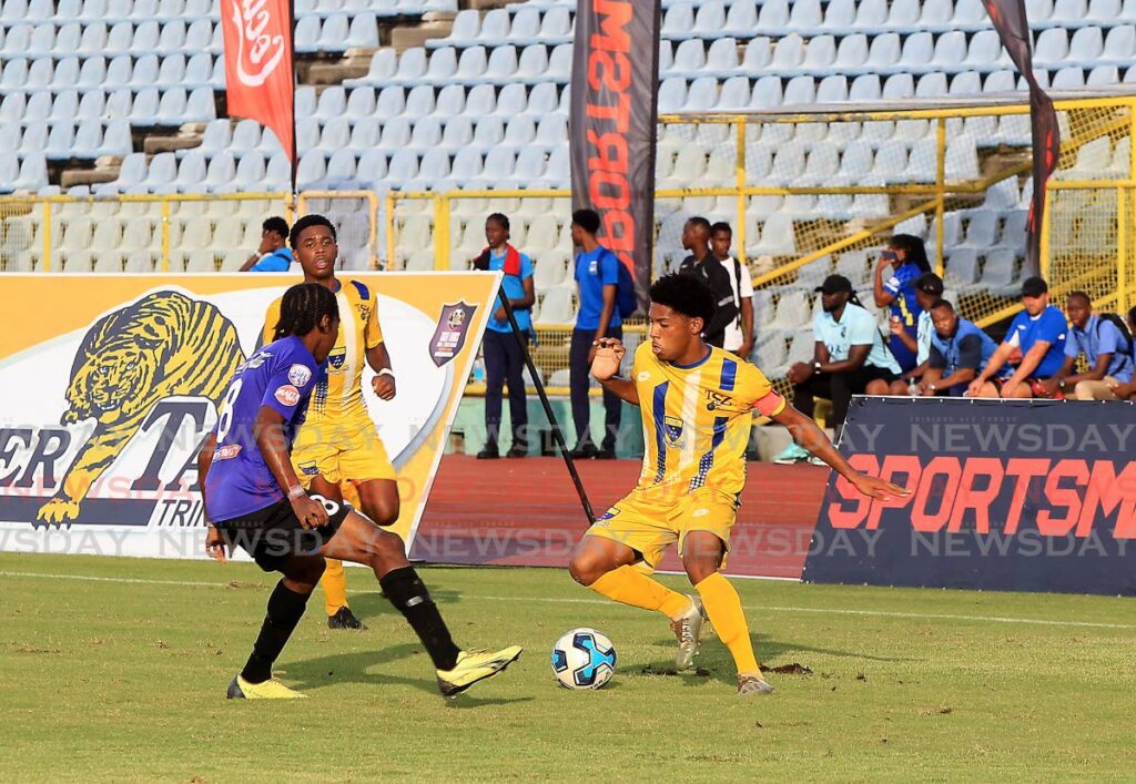 Christian Bailey (right) from Fatima tries to avoid the challenge of East Mucurapo's Khidr Atiba (#18) during the teams' match in the Coca Cola Boys Intercol North Zone semi-final, at the Hasely Crawford Stadium, Mucurapo on Friday. - ROGER JACOB