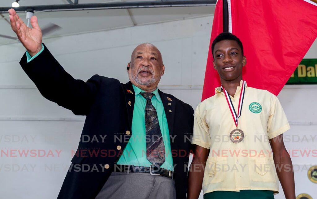 Signal Hill Secondary student Anthonio Hacket proudly displays the Father of the Nation Medal of Honor Bronze, which he received on Monday from Reginald Vidale, chairman of the Dr Eric Williams memorial committee, for finding a wallet containing $5,000 and returning it to its owner. The award ceremony took place at Signal Hill Secondary School. Photo by David Reid