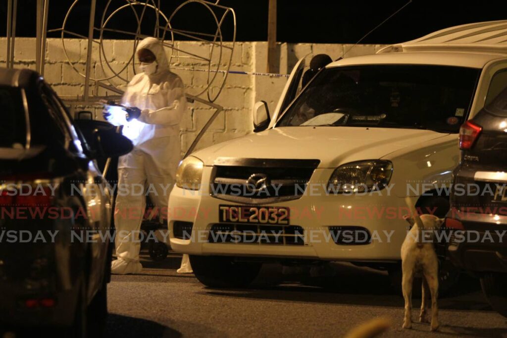 A police crime scene investigator gathers evidence after one man was killed and two others wounded during a gun attack at Pamberi’s panyard, Santa Cruz Old Road, San Juan on Monday. - ANGELO MARCELLE