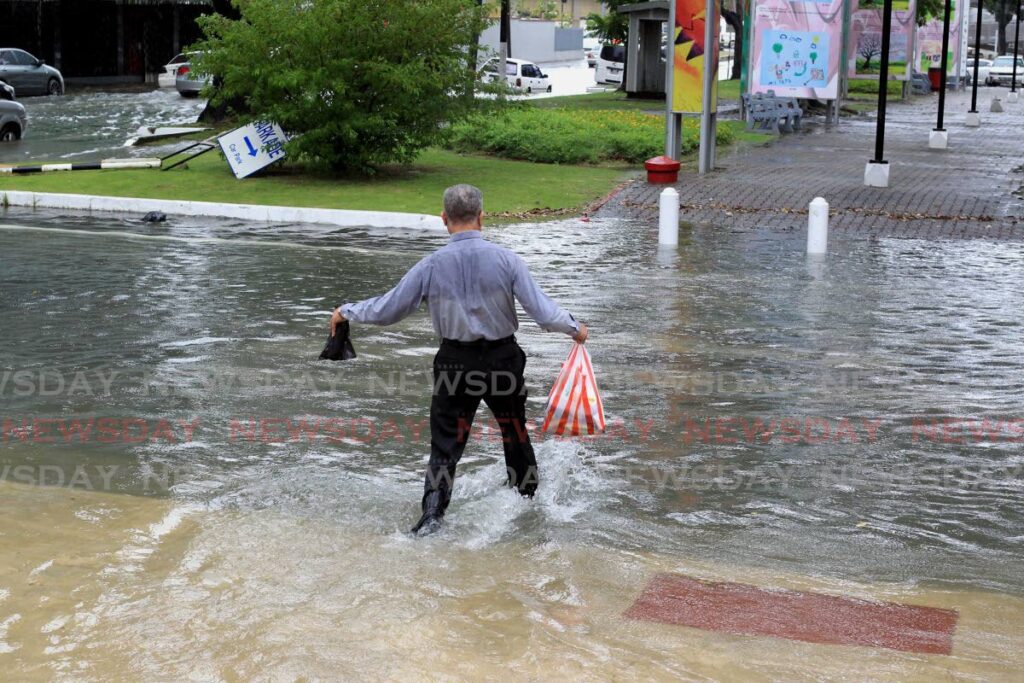 A man wades through floodwaters amid rainfall in Port of Spain on November 17. - Photo by Roger Jacob