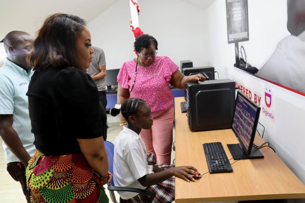 Tobago West MP Shamfa Cudjoe, left, and Digicel Foundation director Georgina Peterkin, right, look on as a student logs into one of the computers at the new homework centre in Golden Lane.  - 
