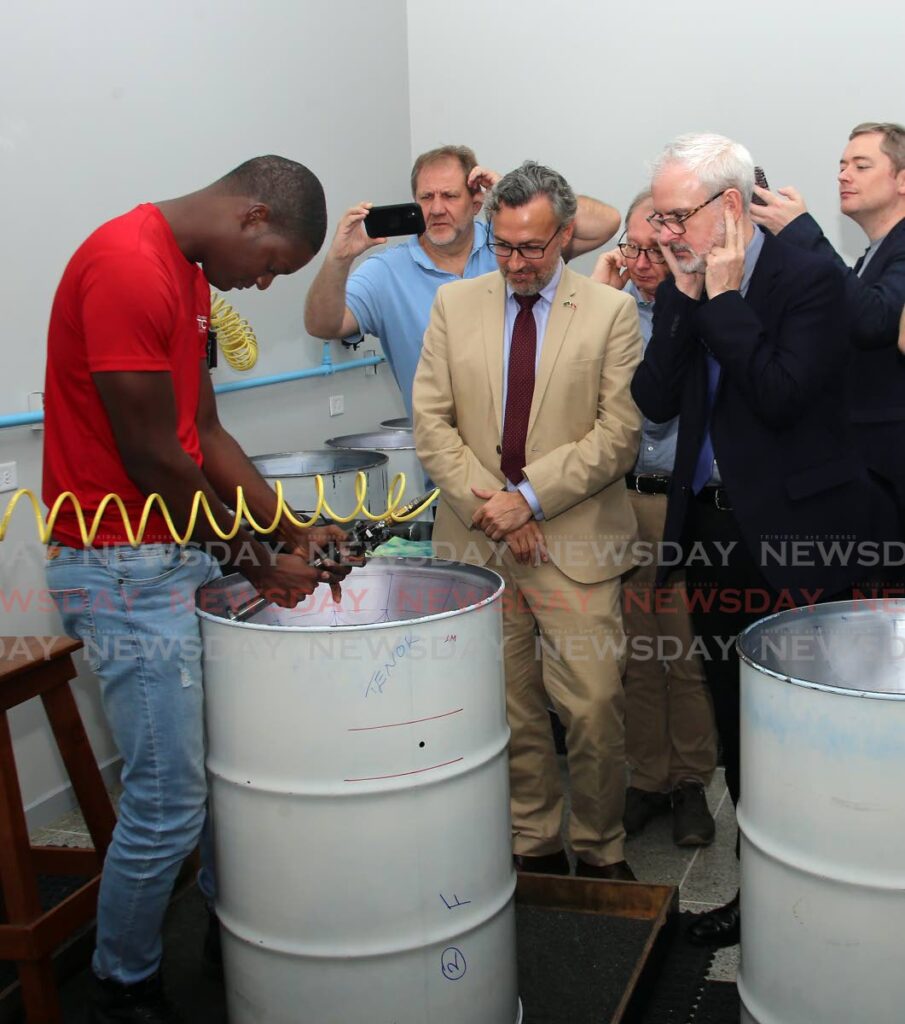 MITTCO employee Jaijah Codrington shows how a steel pan is made to COLAC chair Tomas Ortegas Reyes, centre, and EU Ambassador Peter Cavendish in Diego Martin on Saturday. - SUREASH CHOLAI