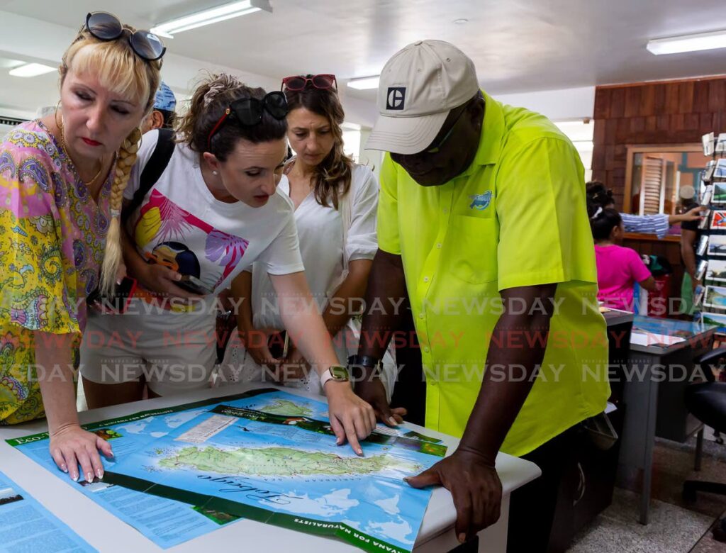 Tourists from the Rhapsody of the Seas cruise ship check out a map of Tobago as they plan their tours with taxi drivers at the Scarborough port on Monday, - DAVID REID