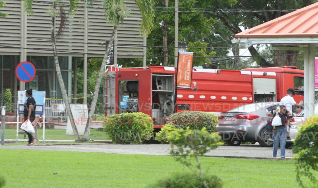 People walk past a fire truck at UWI, St Augustine, on Friday after a fire brke out at the Lloyd Braithwaite Student Administration Building on Thursday night. - Angelo Marcelle