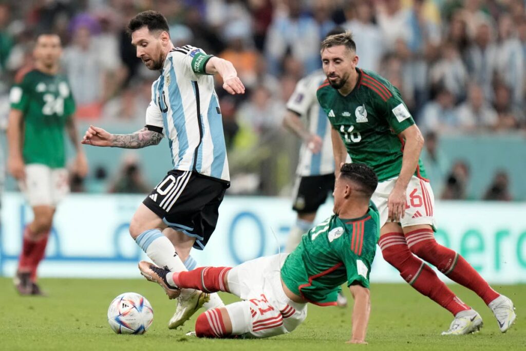 Mexico's Uriel Antuna, on the ground, tries to tackle Argentina's Lionel Messi during the World Cup group C match, at the Lusail Stadium in Lusail, Qatar, on Saturday. (AP Photo) 