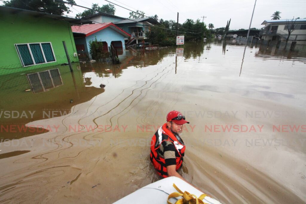 WATER TAXI: Disaster volunteer Edwin Amrit leads a dinghy through chest-high floodwaters in Bamboo #2 where several stranded families had to be rescued. PHOTO BY ANGELO MARCELLE - ANGELO MARCELLE