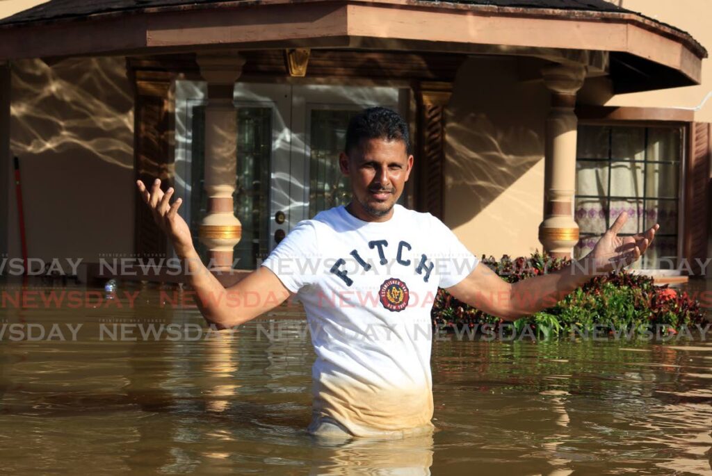 A resident stands in disbelief in waist-high floodwater near his home on Nabbie Street, Bamboo No 2, Valsayn South on Tuesday. - ROGER JACOB