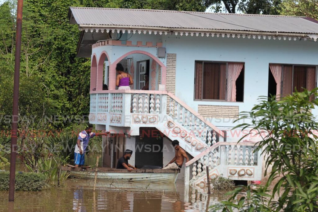 Helpful citizens use a boat to assist residents marooned at home on Chrysostom Street, Mafeking Village, Mayaro due to severe flooding. Photo by  Lincoln Holder