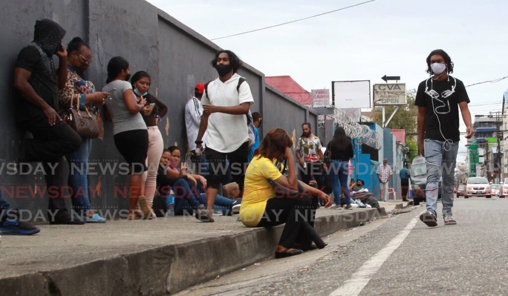 Mirgants wait to enter the Immigration Office on Henry Street in Port of Spain. - ROGER JACOB