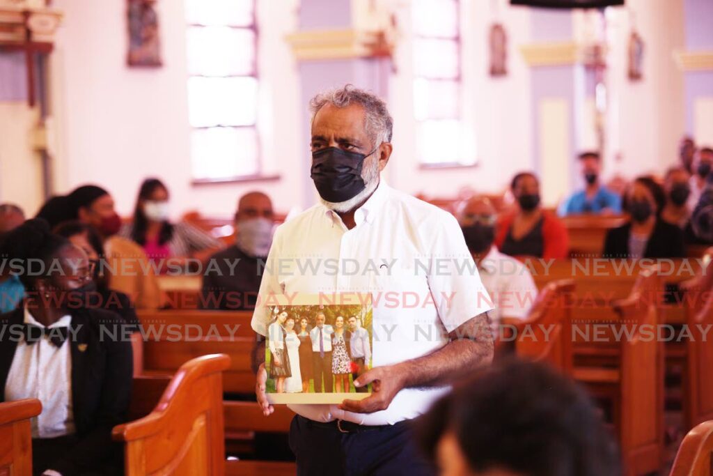 Kazim Ali Snr carries a family photograph that includes his son Kazim Jr, one of four divers who died in the Paria pipeline disaster, during a memorial at Our Lady of Perpetual Help RC Church, San Fernando on March 8. Photo by Lincoln Holder