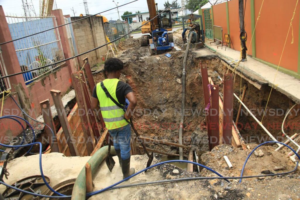 A worker looking down at the repair work being done on the  sinkhole at CCC Boulavard  in the Beetham Gardens  which is one  of the more major of the three sinkholes to have developed in the area believed to be caused by a collapsing underground sewer line. Photo by Sureash Cholai