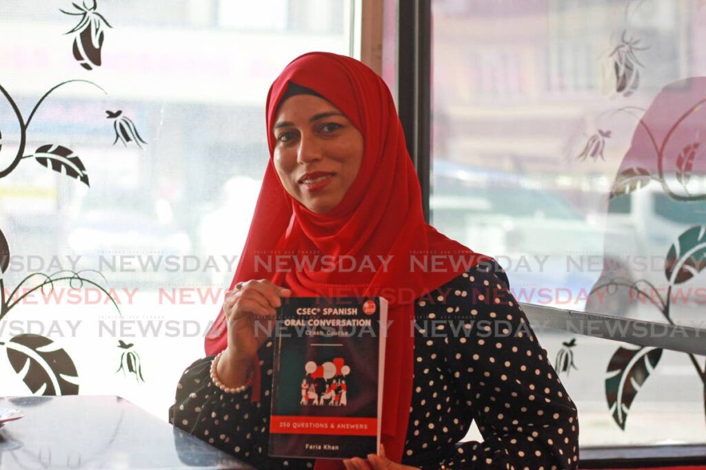 Secondary school Spanish teacher Faria Khan with a copy of the book she wrote for students on CSEC Spanish orals. - Marvin Hamilton