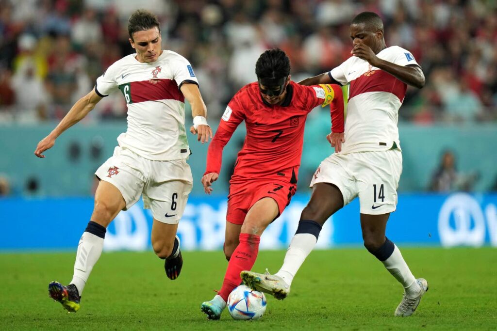 South Korea's Son Heung-min, centre, dribbles through Portugal's Joao Palhinha, left,  and William Carvalho during their World Cup group H match, at the Education City Stadium in Al Rayyan, Qatar, Friday.  (AP photo)