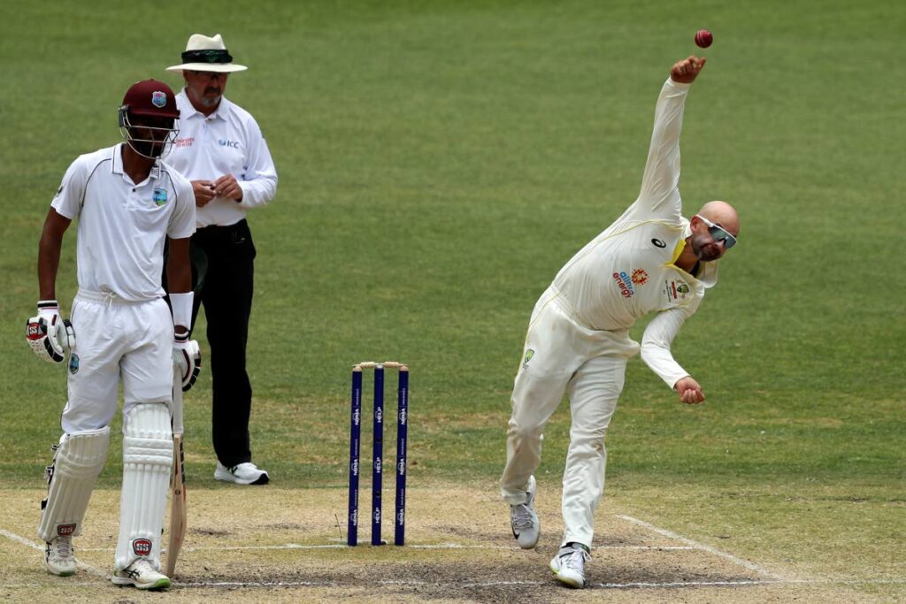 Australia's Nathan Lyon, right, bowls as West Indies' Roston Chase, left, watches on the 5th day of their Test in Perth, Australia, Sunday. (AP photo)