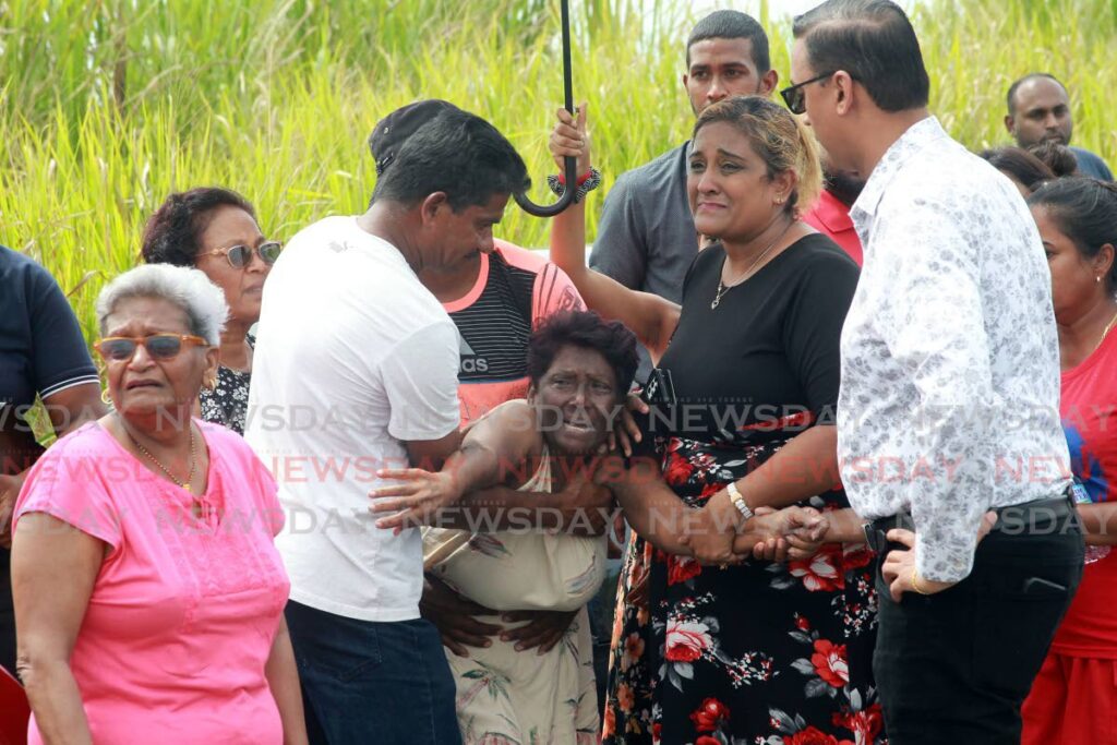 IN GRIEF: Grieving relattives gathered at Factory Road, Chaguanas, where the bodies of murdered couple, Amar Randy Ramdass and Anita Jagdeo, were found in a car on a dirt road, on Sunday.
Also on the scene was Couva North MP Ravi Ratiram who said he knew the couple.

Photo by Lincoln Holder