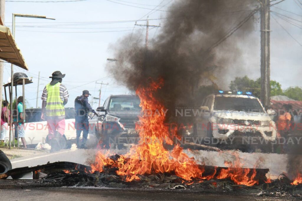 Police arrived at Vessigny Village where residents and taxi drivers burnt debris on Monday morning to protest bad road conditions. - Marvin Hamilton