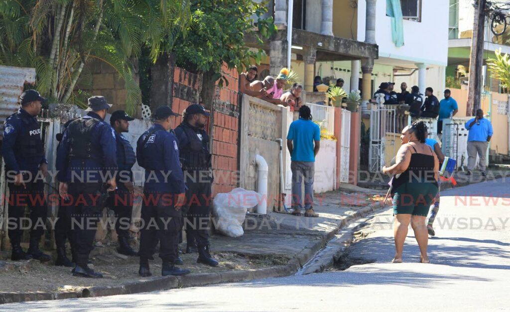 A woman speaks with police at Chrysanthemum Drive in Morvant where two men were shot dead in an alleged shootout with police on Tuesday. Photo by Roger Jacob