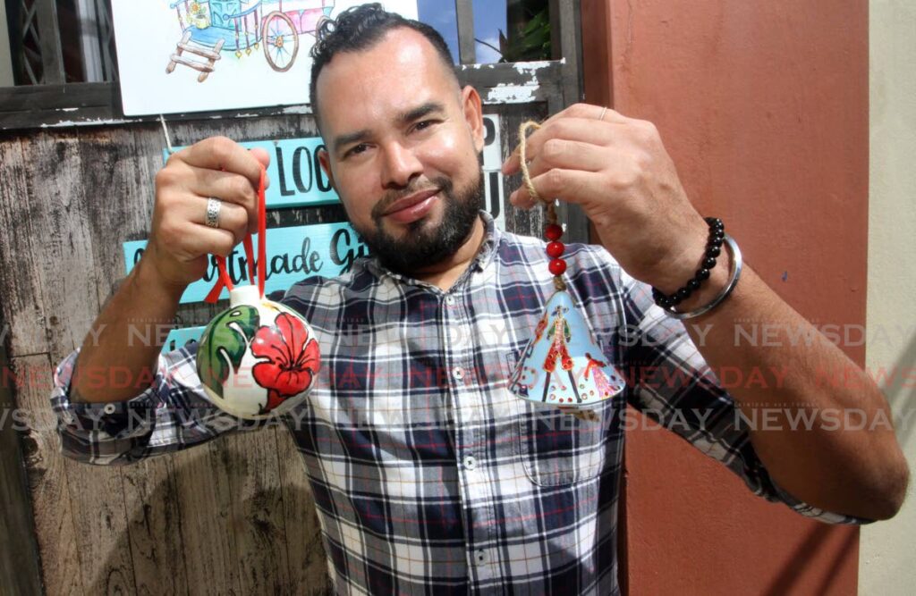 Artist Damian Moore holds Carnival and floral-themed ornaments designed for Christmas trees. - Angelo Marcelle