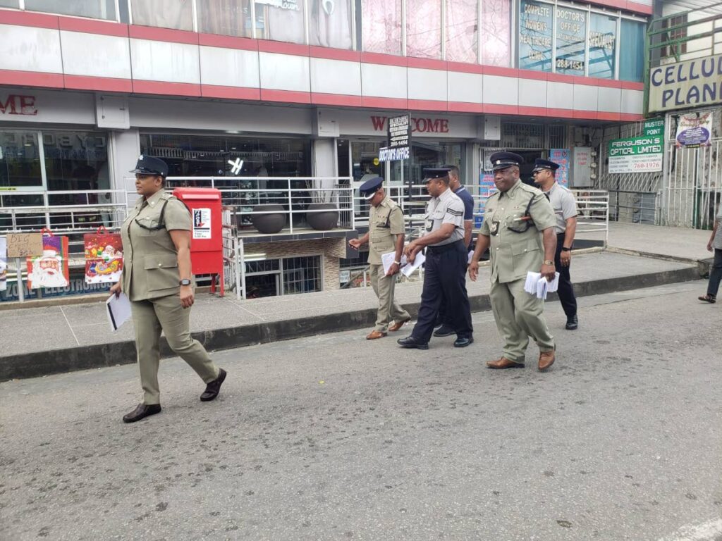 Regular and municipal police walk through Princes Town on Friday. 