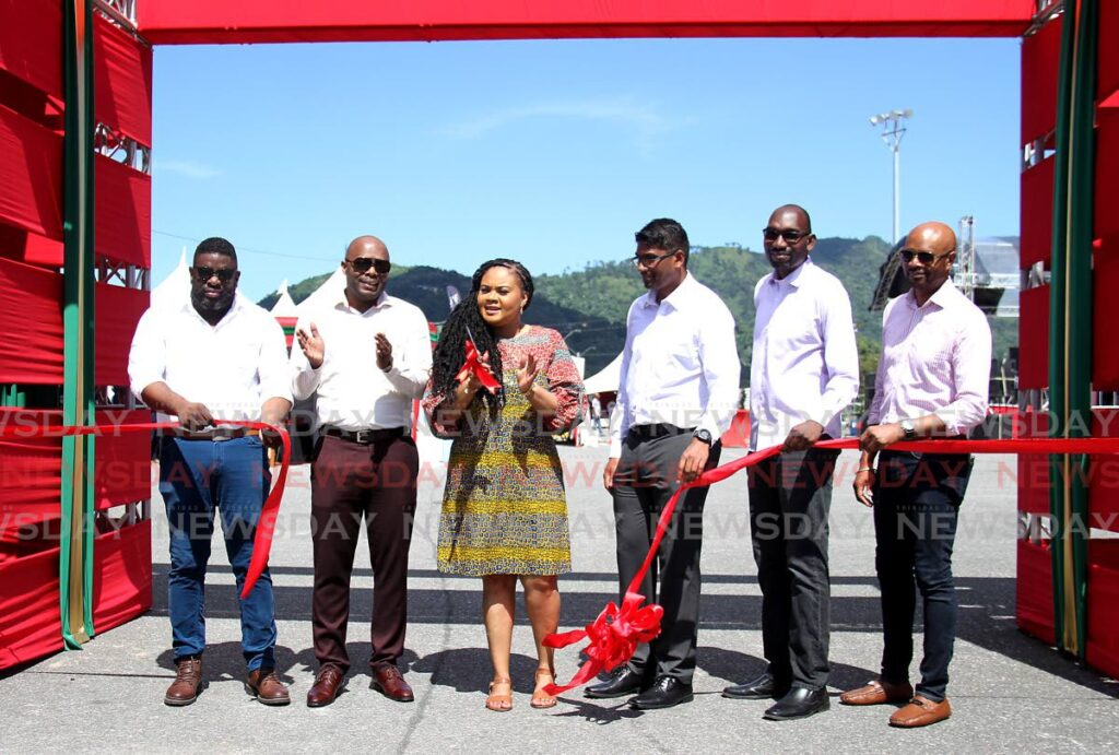 Minister of Sport and Community Development Shamfa Cudjoe, centre, cuts the ribbon with, from left, TSTT acting manager, emerging services and innovation Keino Cox, ExporTT chairman Roger Roach, ExportTT general manager Dhanraj Harrypersad, Export Centres Co Ltd CEO Adwin Cox, and Export Centres deputy chairman Montgomery Guy during the opening of the Craft Hub TT Christmas Village at Queen’s Park Savannah, Port of Spain on Saturday. - AYANNA KINSALE
