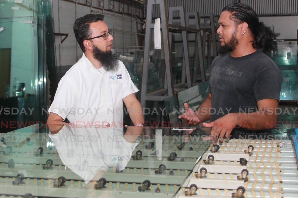 Kameel Khan and an employee discuss a job at Kamri Glass in Point Lisas. Photo by Marvin Hamilton
