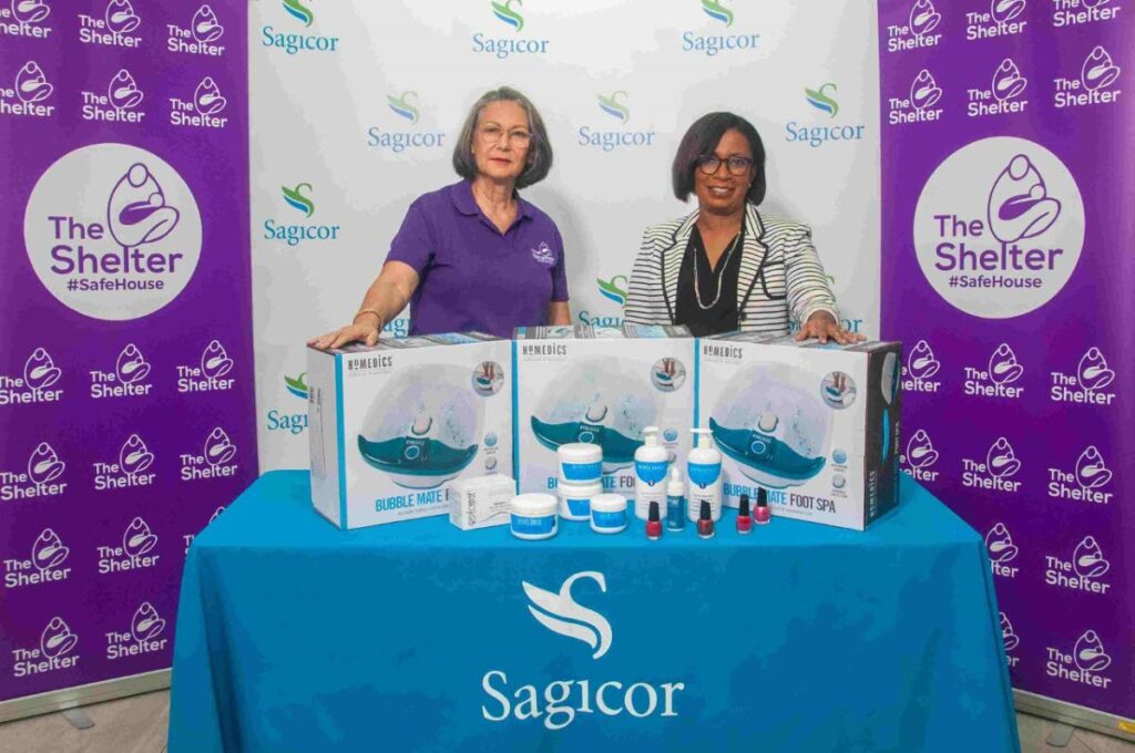 Sagicor human resources vice president Michelle Bell-Sookhoo, right, presents vice chair Sherron Harford with the funds to support The Shelter’s new skills training workshop in aesthetics. - 