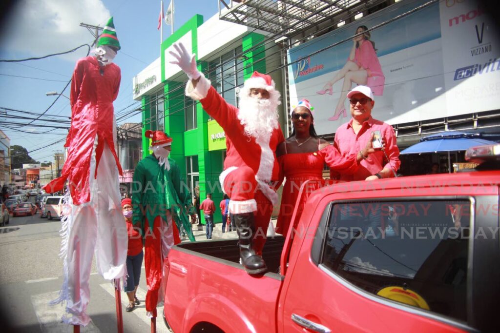 Fire officer Justin Kee Fatt as Santa Claus and Ann Samaroo, PRO for the Greater San Fernando Chamber of Commerce and Chamber president Kiran Singh spread Christmas cheer along High street San Fernando on Friday.  Photo by Lincoln Holder