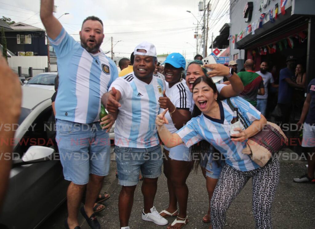 Argentina supporters celebrating on Ariapita Avenue in Woodbrook on Sunday after their team won the 2022 FIFA World Cup. Martin Baritto, second from left, and Edith Shaw, second from right, were among those happy with the result. - SUREASH CHOLAI