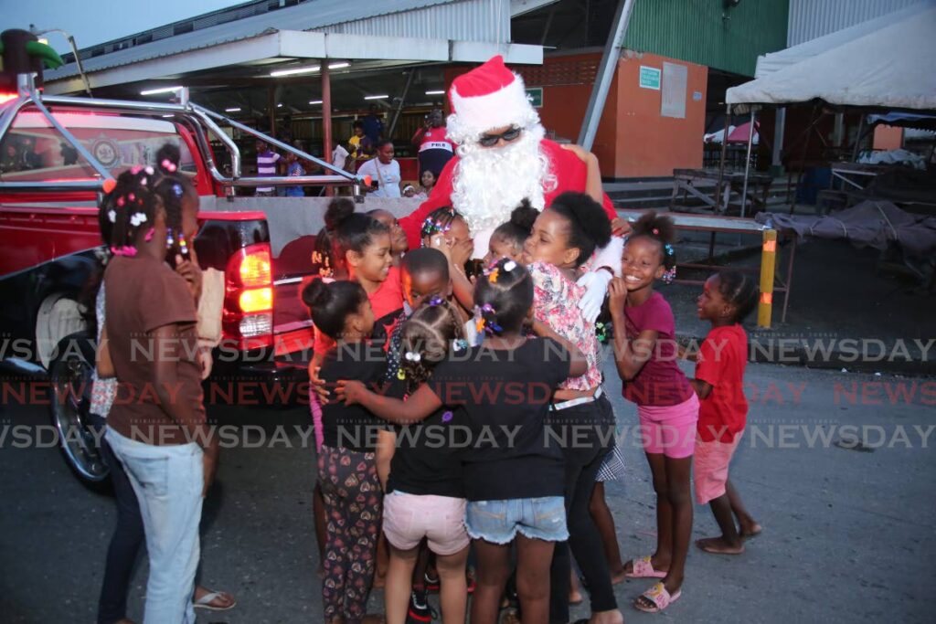 Santa Claus is surrounded by children as he arrives at the fifth annual children's Christmas party hosted by the Port of Spain City Police, at the Central Market, on Sunday afternoon. Photo by Shane Superville