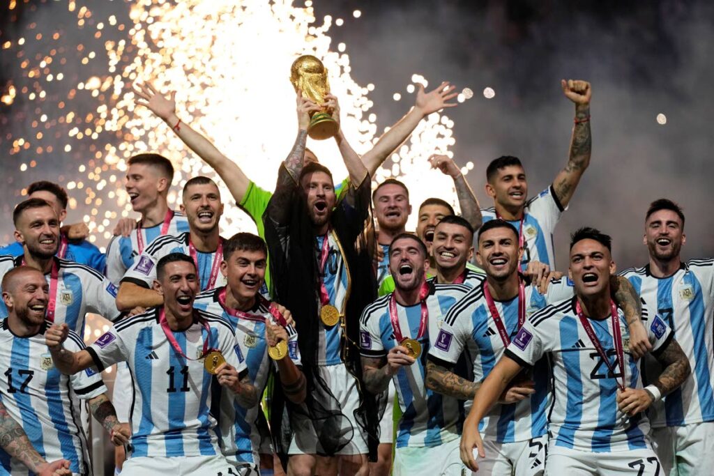 Argentina captain Lionel Messi lifts the World Cup trophy surrounded by his teammates, after beating France 4-2 in a penalty shootout on Sunday at the Lusail Stadium in Qatar.   (AP PHOTO)