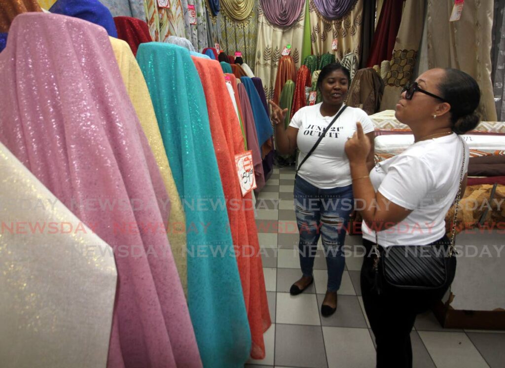 Two women shop for cloth at Miguel Moses, Queen Street, Port of Spain, on Monday.