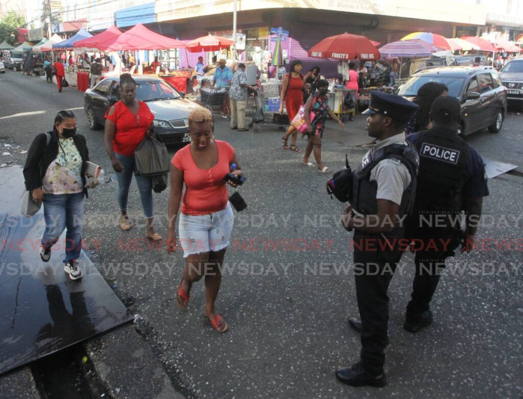 Police officers oversee shopping on Charlotte Street, Port of Spain, on Monday. Photo by Angelo Marcelle