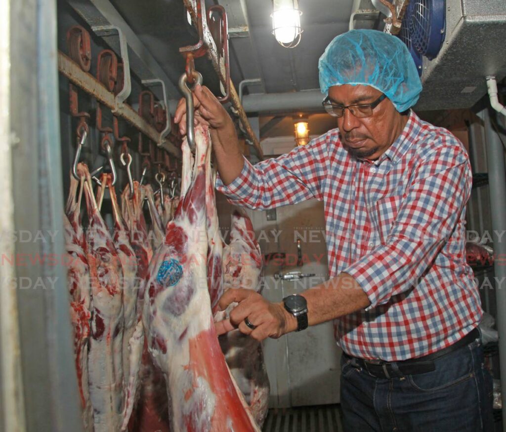 Agriculture, Land and Fisheries Minister Kazim Hosein examines freshly slaughtered goat carcasses on Monday during a tour of the Sugarcane Feed Centre in Longdenville. PHOTO BY MARVIN HAMILTON - 