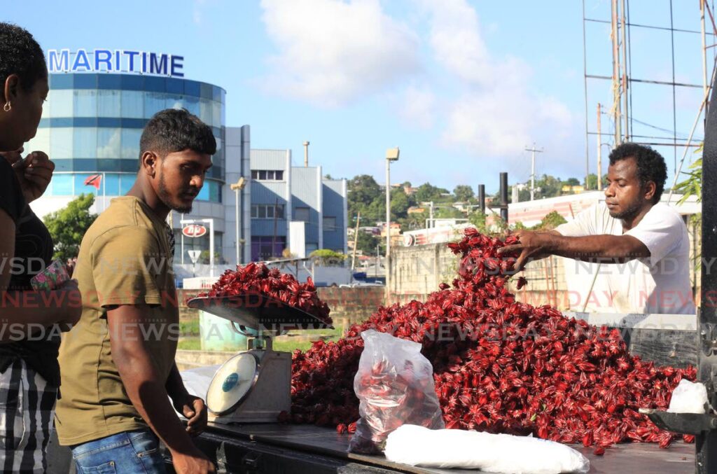 Vendor Ricky Caton parcels sorrel for a customer at Maritime Roundabout, Barataria on Wednesday. Photo by Roger Jacob