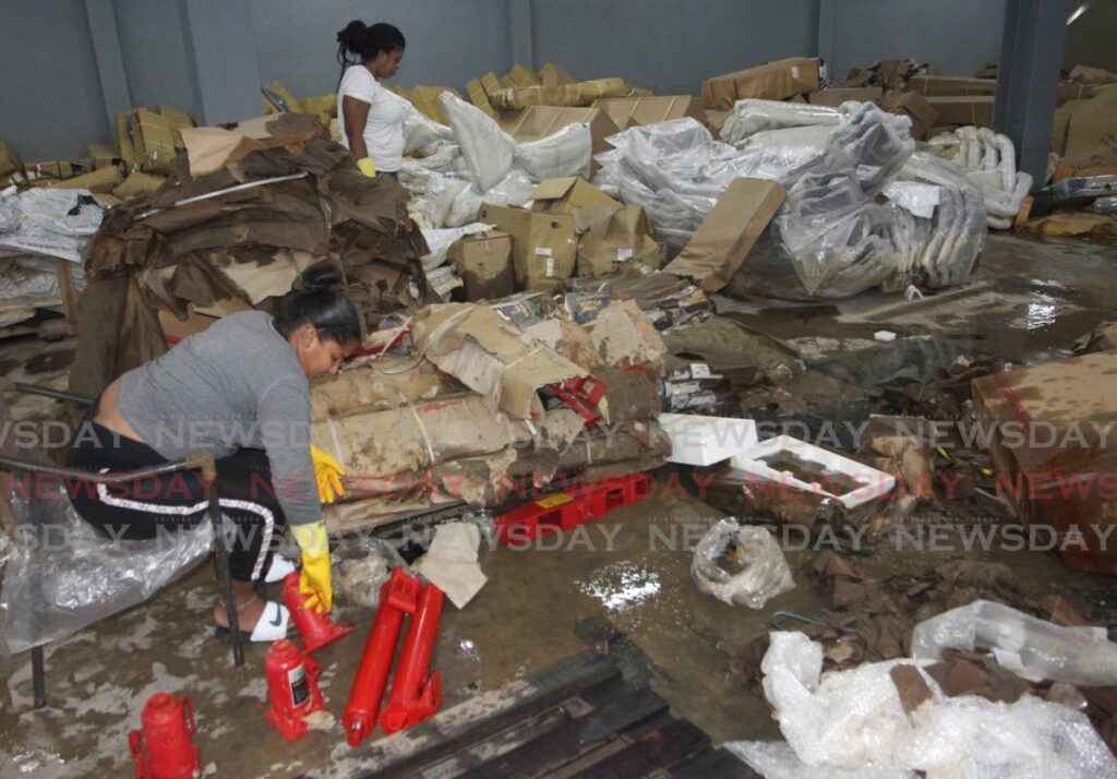 Workers of Bobby's Motor Supplies in Bamboo #2 sift through mounds of wet bags and boxes in the warehouse on Thursday, a month after the building was flooded out. 