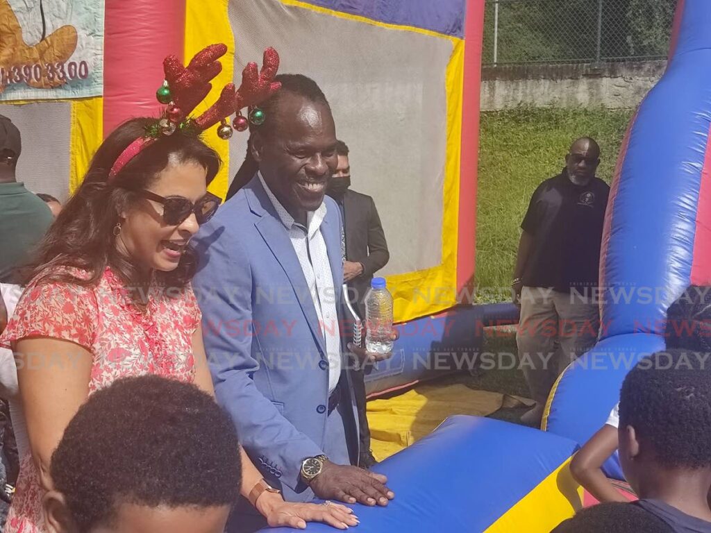 US Ambassador to TT Candace Bond, left, and National Security Minister Fitzgerald Hinds look at children playing on a bouncy castle during the seventh annual Christmas on the Hill, Christmas treat for children at Sogren Trace, Laventille, on Friday. Photo by Shane Superville