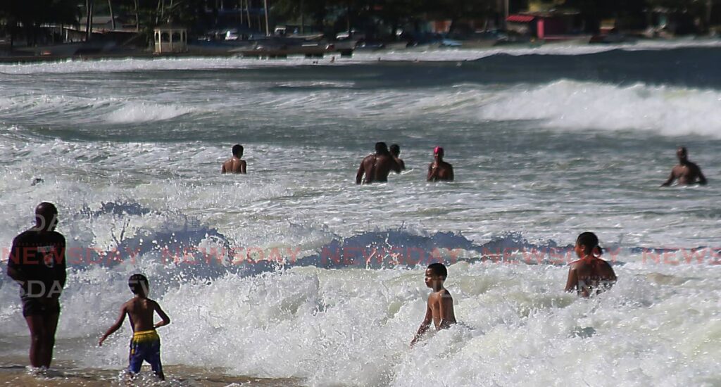 DANGER SWIM: Bathers including children bathe in the rough waters of Maracas Bay on Friday, the start of an orange-level alert which runs through the extended Christmas weekend. PHOTO BY SUREASH CHOLAI - 