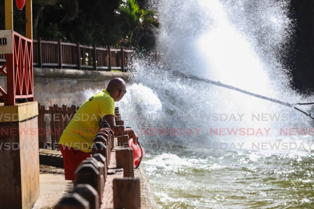 Lifeguard Roger Dwarika looks at swells crashing onto the shore at Macqueripe beach on Saturday. Jeff K Mayers