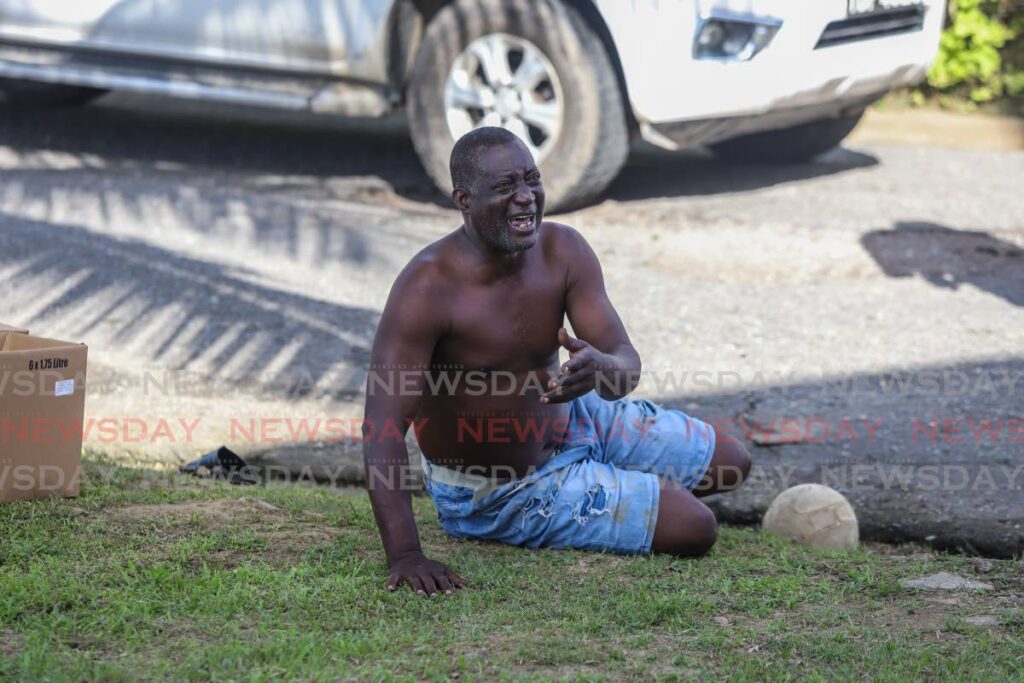 Overcome by grief, this man falls to the ground after seeing the body of his nephew Isaiah Commissiong who was shot dead by an unknown man at the La Horquetta recreation ground on Sunday. - JEFF K MAYERS