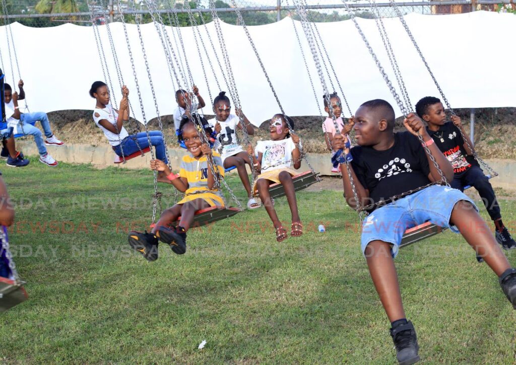 SWINGING FUN: Children play on the swings as the Inter-Agency Task Force's Youth Club held its annual Children's Xmas Treat in the Beetham Garden's recreational grounds. Photo by Roger Jacob