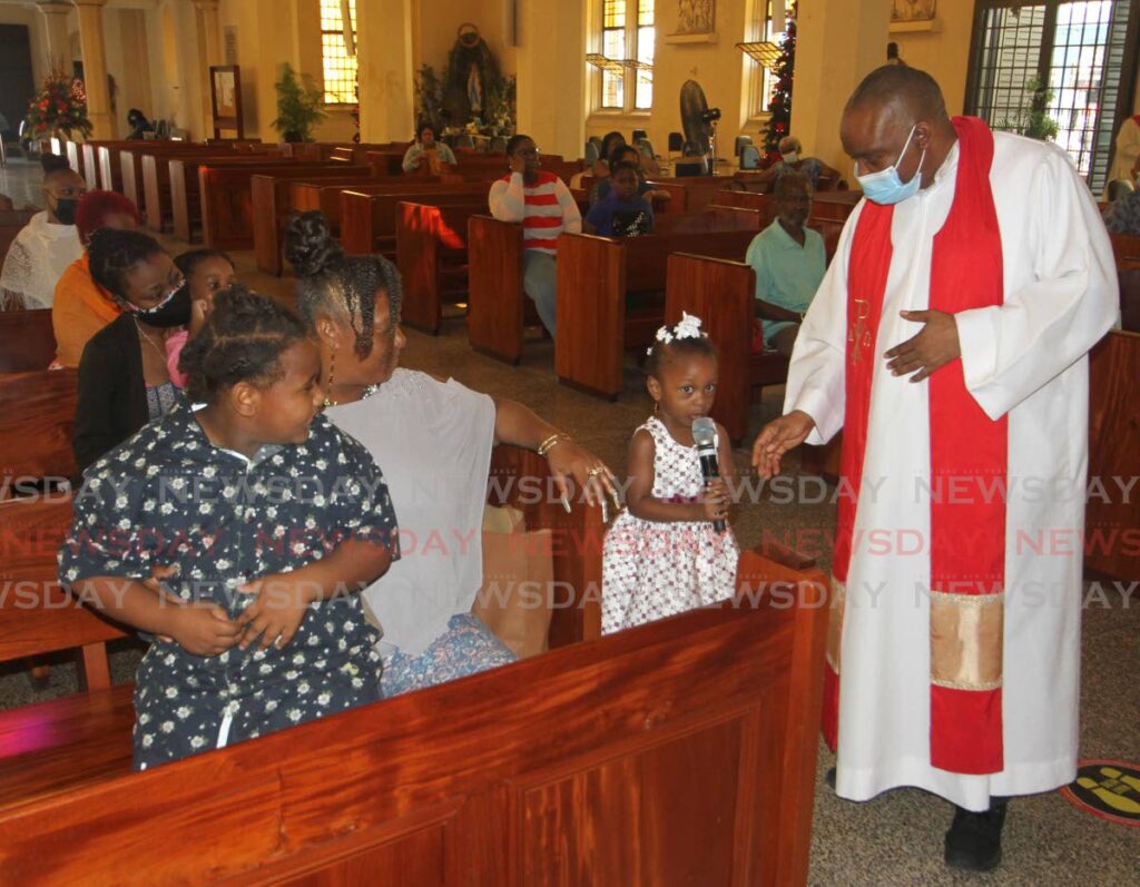 Little Kalia Christopher, three, second from right, tells Fr Emmanuel Dafe and the congregation about her christmas gift, at a mass to mark the Feast of the Holy Innocents at The Cathedral of the Immaculate Conception, Port of Spain on Wednesday. - Angelo Marcelle