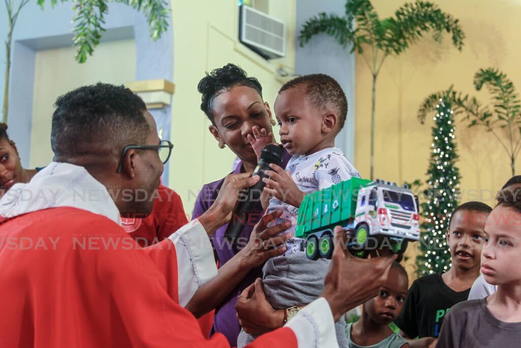 [MAIN] Fr Jayson Grell, left, speaks with a young boy about his toy truck during a mass to mark the Feast of the Holy Innocents at Our Lady of Perpetual Help church, Harris Promenade San Fernando on Wednesday. - Marvin Hamilton